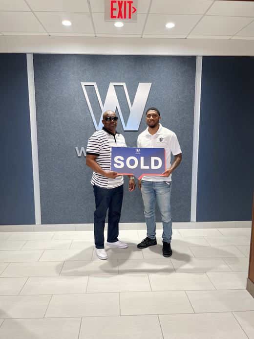 Jamari Toney with a seller at closing, holding a sold sign