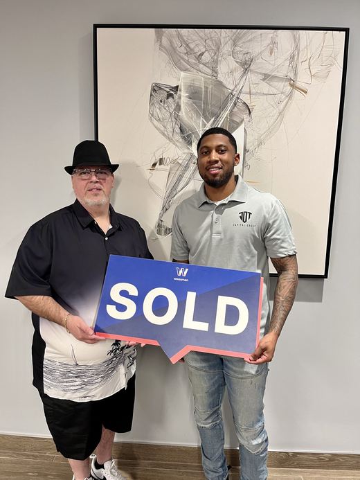 Jamari Toney with a seller at closing, holding a sold sign